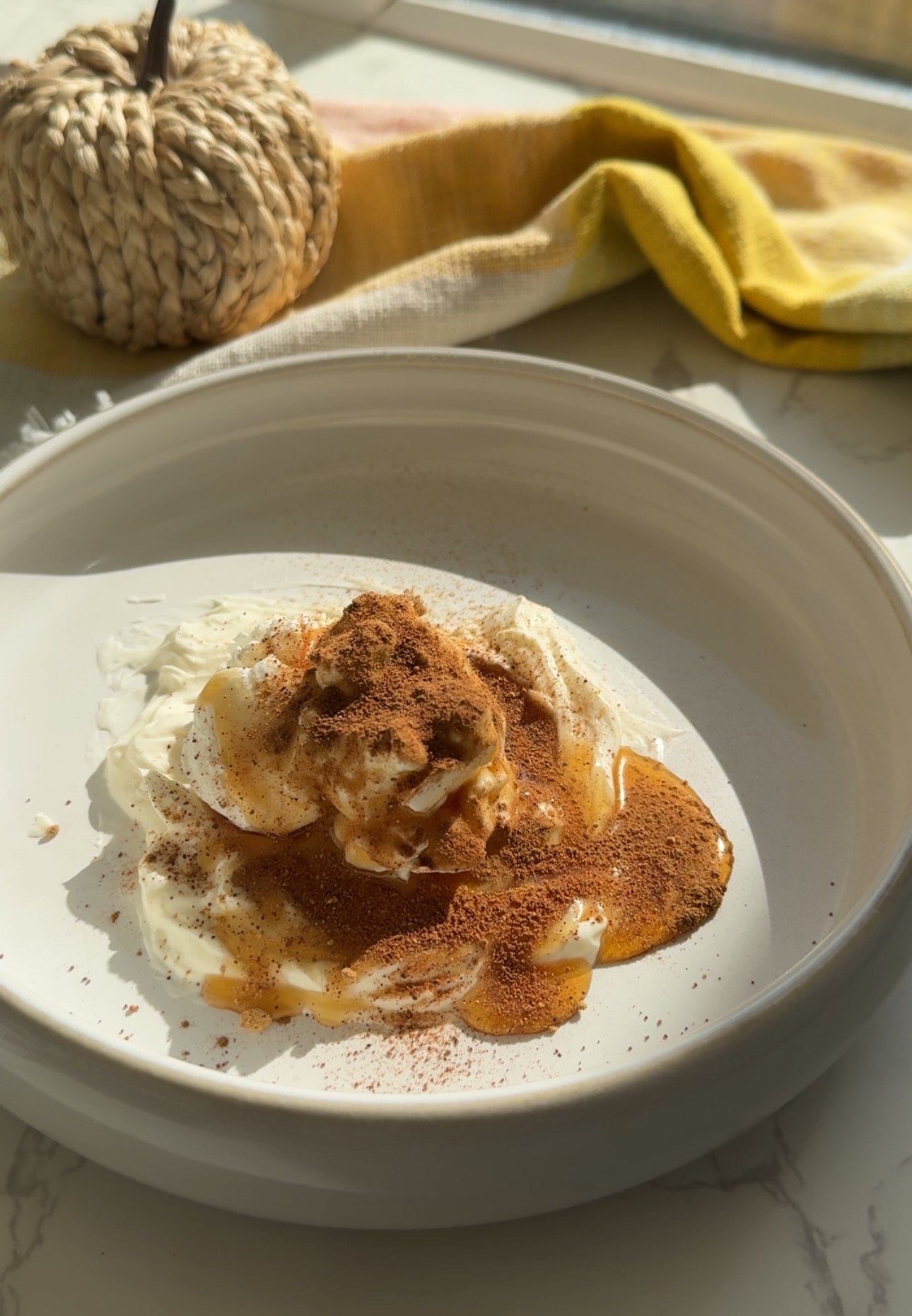 Pumpkin spice cheesecake protein balls coated in cream cheese icing on parchment paper