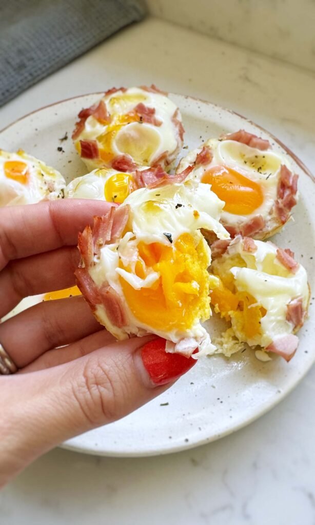 Ham and Cheese Egg Bites, one bit tin half held in hand