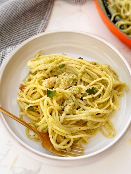 Creamy zucchini and chicken pasta served in a white bowl with fresh parsley garnish