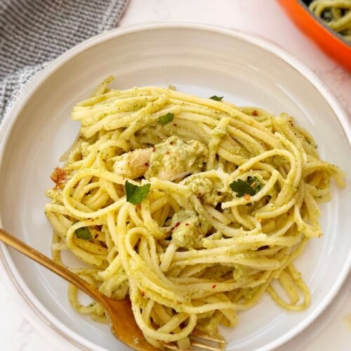 Creamy zucchini and chicken pasta served in a white bowl with fresh parsley garnish