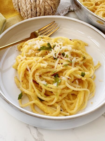 Bowl of creamy roasted pumpkin pasta garnished with parsley