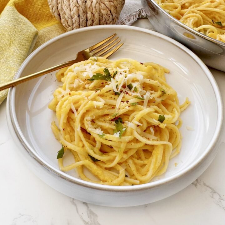 Bowl of creamy roasted pumpkin pasta garnished with parsley