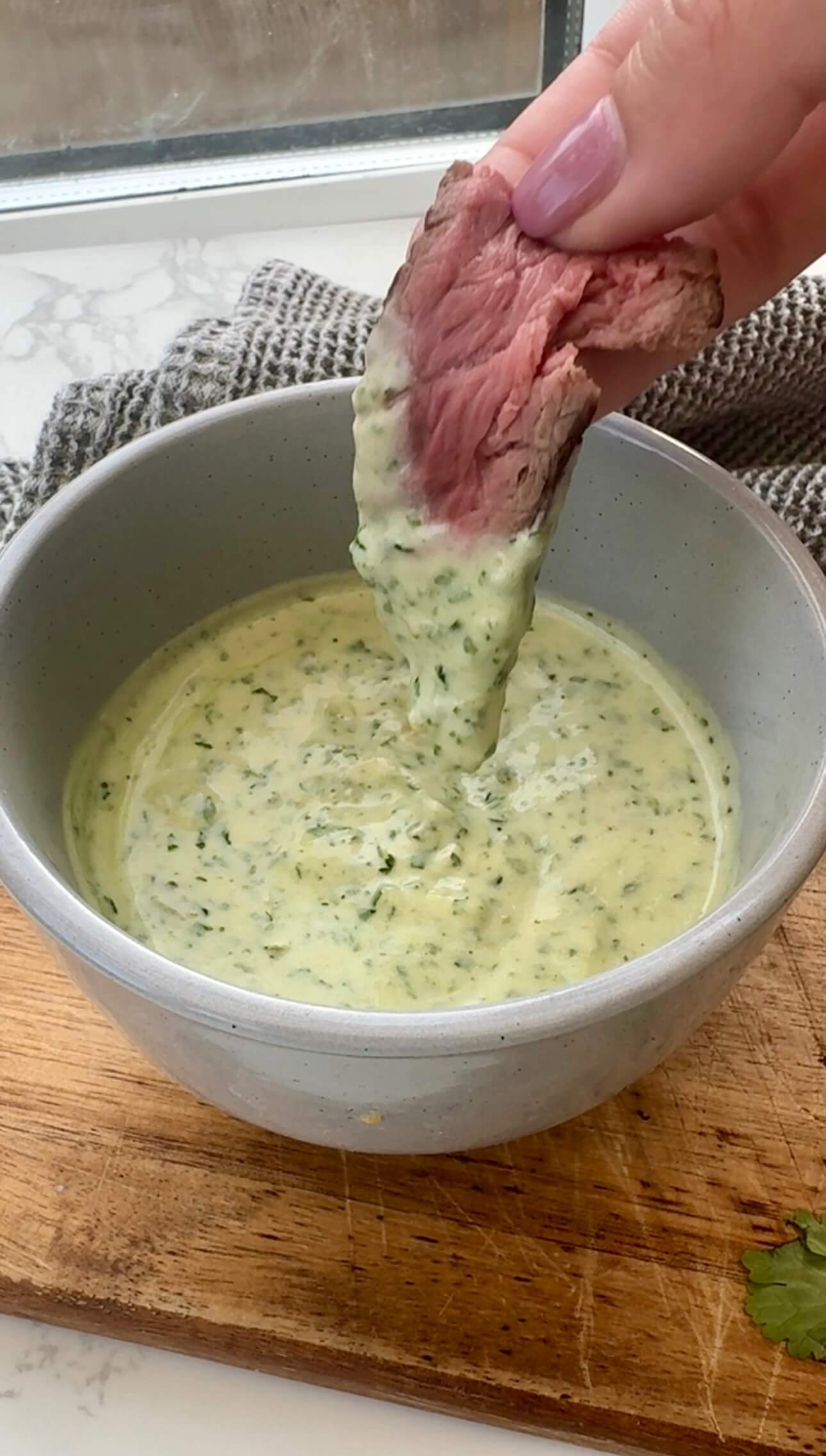Latin American steak sauce served in a bowl with a piece of steak dipped in it.