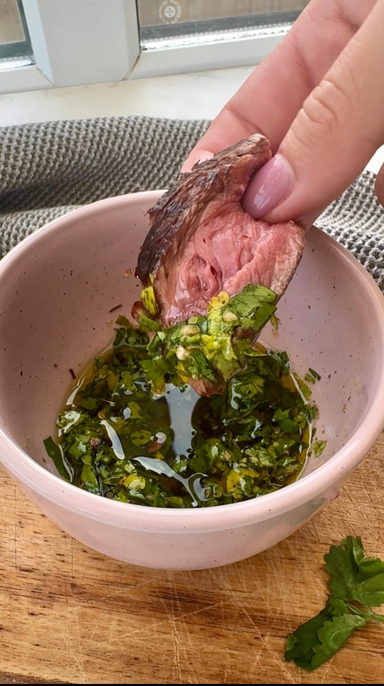 Latin American steak sauce served in a bowl with a piece of steak dipped in it.