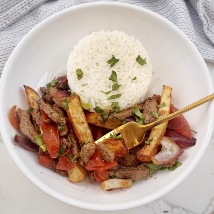Plate of Lomo Saltado with beef, onions, tomatoes, fries, and rice – an authentic Peruvian stir-fry.