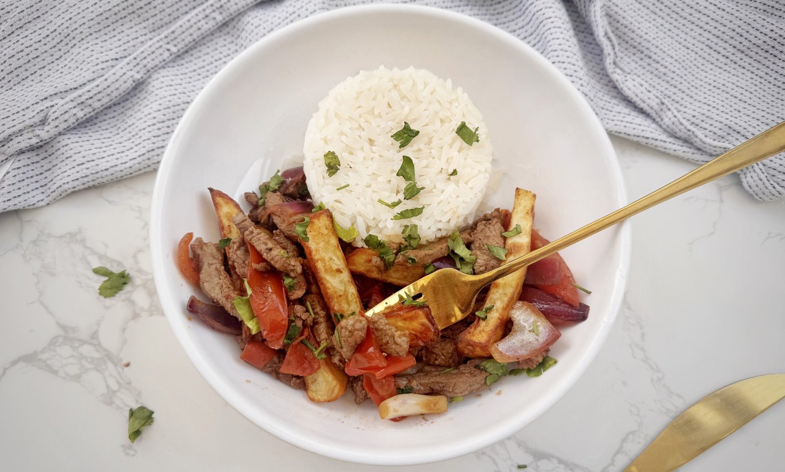 Plate of Lomo Saltado with beef, onions, tomatoes, fries, and rice – an authentic Peruvian stir-fry.