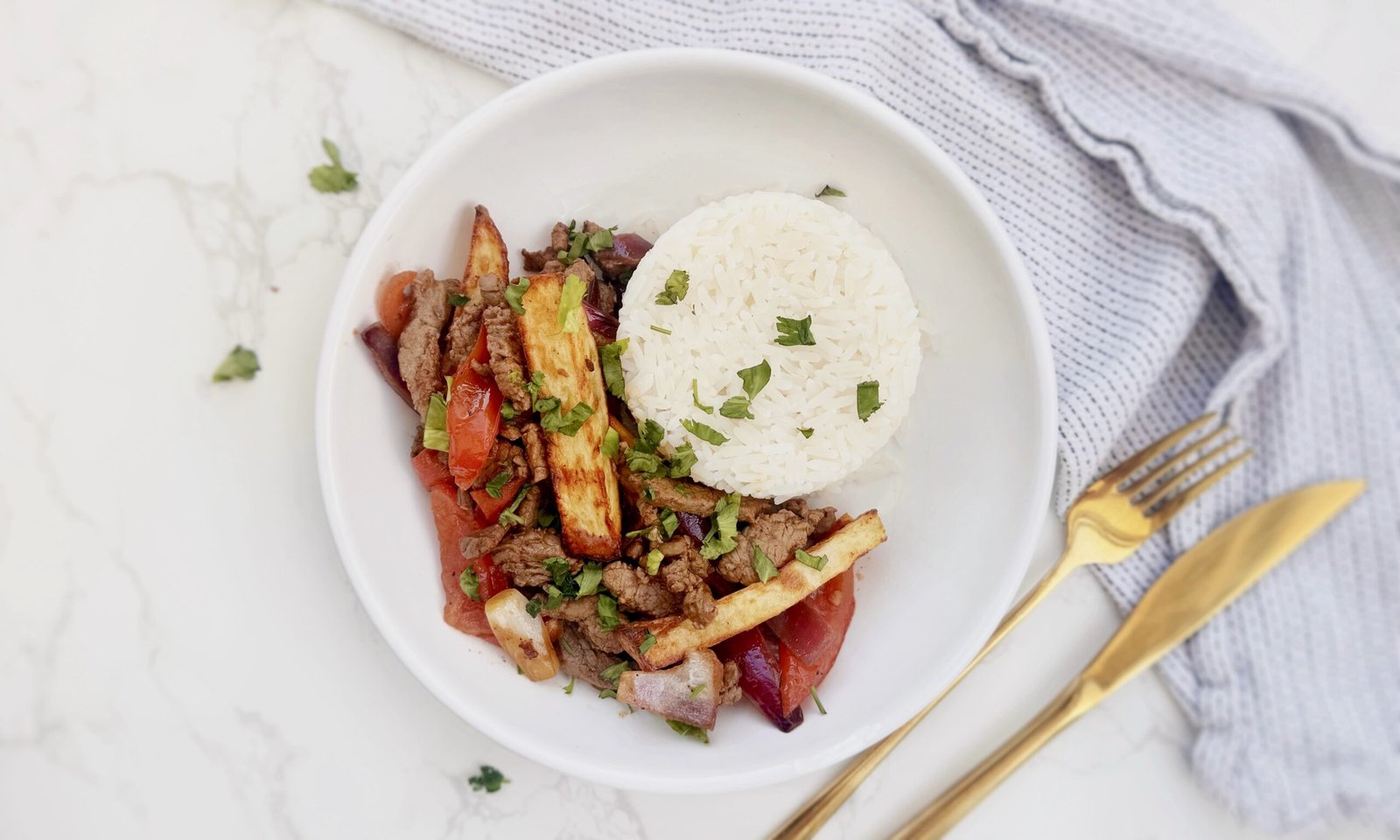 Plate of Lomo Saltado with beef, onions, tomatoes, fries, and rice – an authentic Peruvian stir-fry.
