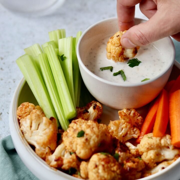 Parmesan Cauliflower Buffalo Bites with Greek Yogurt Ranch, a bite dipped in the yogurt ranch