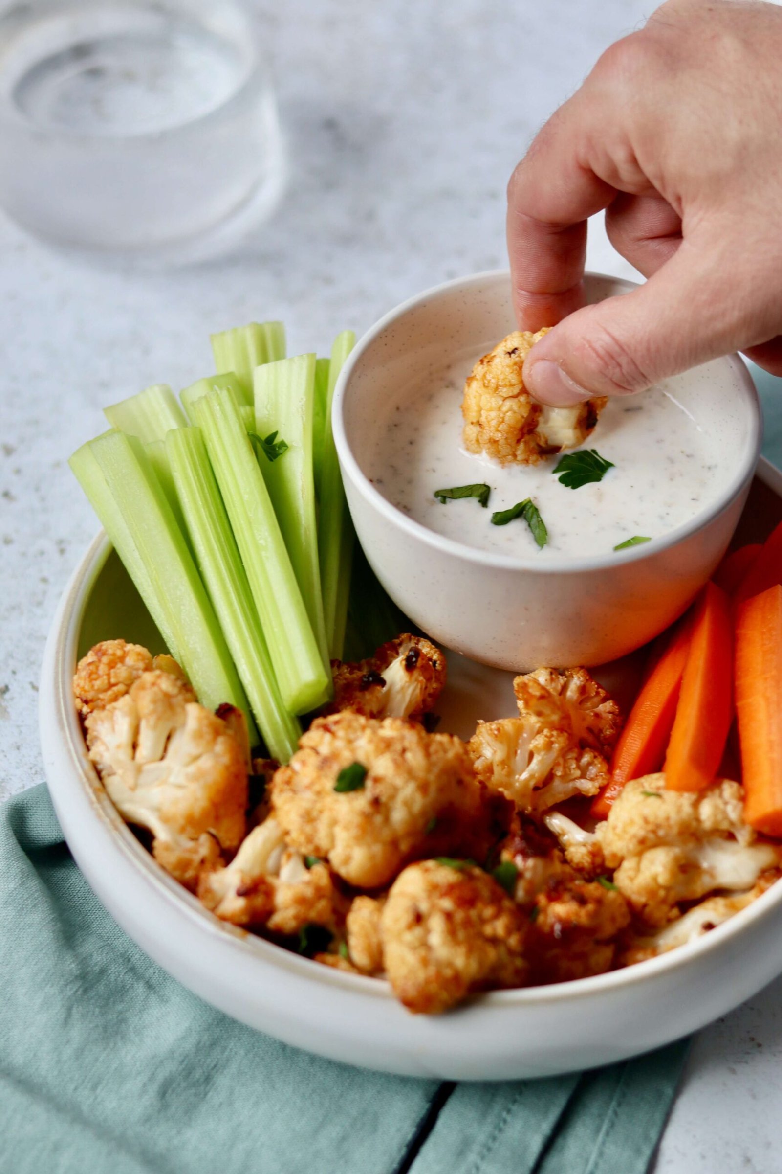 Parmesan Cauliflower Buffalo Bites with Greek Yogurt Ranch, a bite dipped in the yogurt ranch