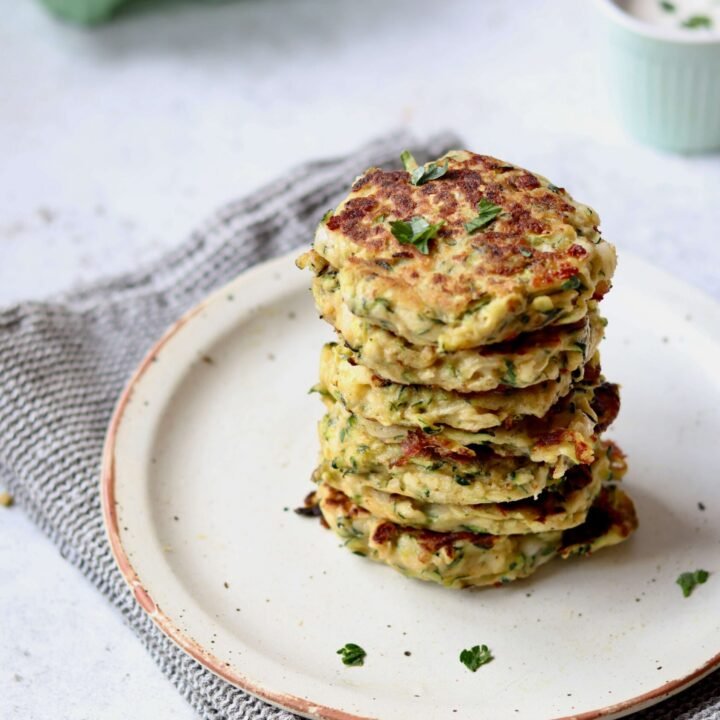Cheesy Zucchini Fritters with Herbed Greek Yogurt Dip arranged over a plate