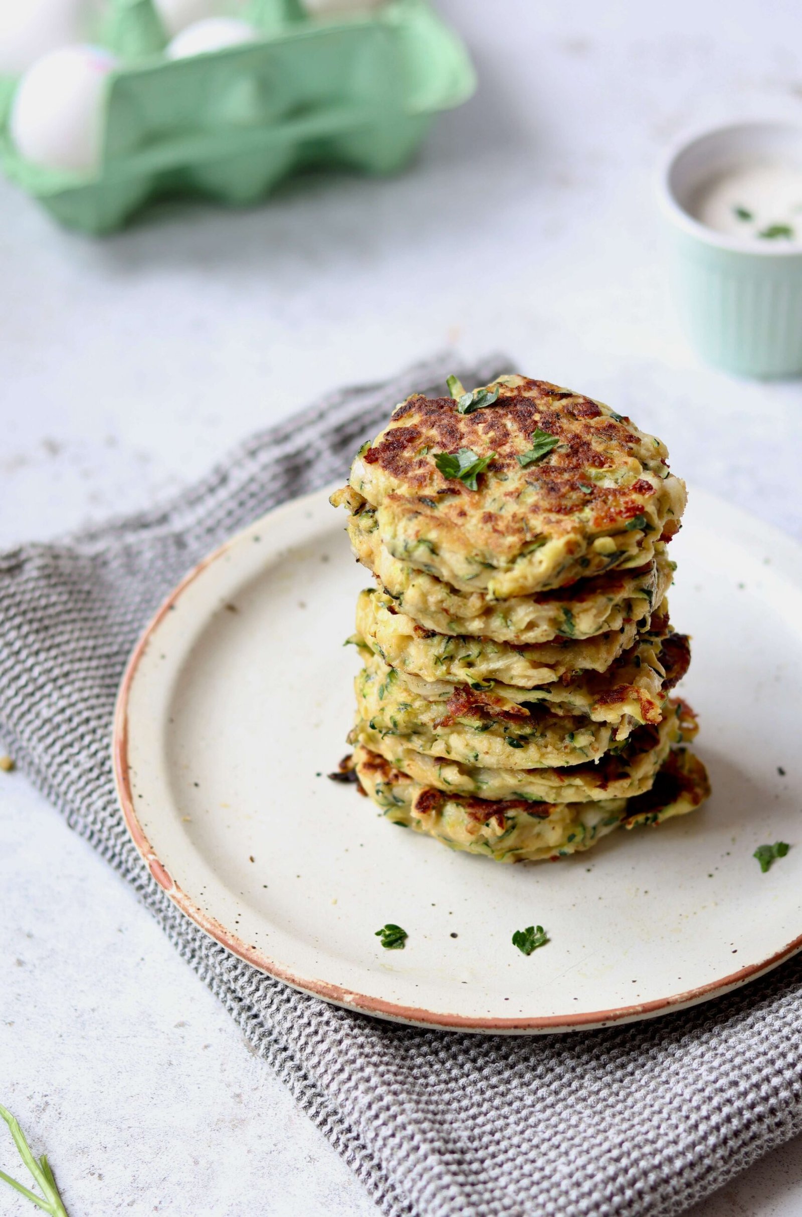 Cheesy Zucchini Fritters with Herbed Greek Yogurt Dip arranged over a plate