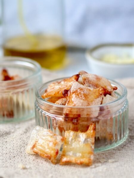 Cheese and onion rice paper chips piled in a small glass dish, golden and crisp