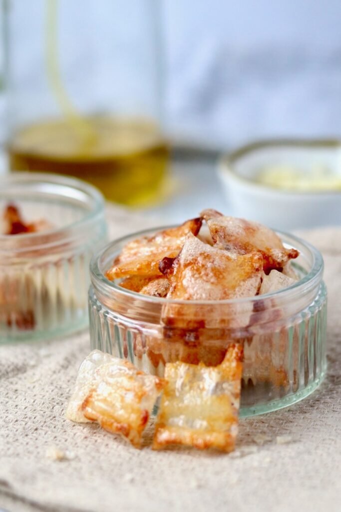 Cheese and onion rice paper chips piled in a small glass dish, golden and crisp