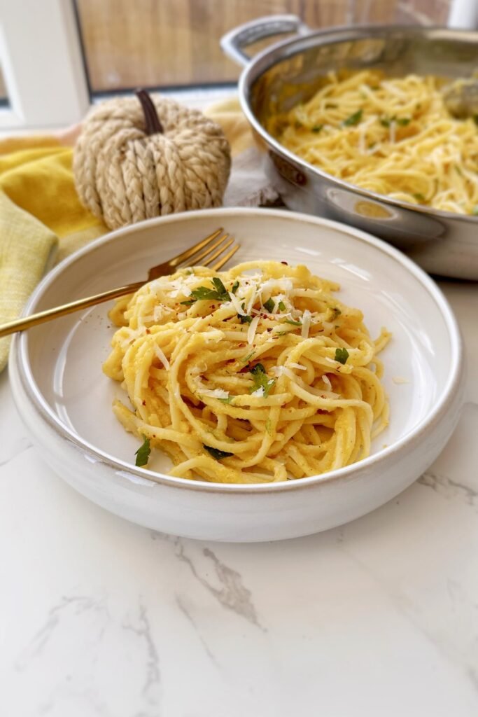Creamy pumpkin pasta twirled in a bowl with a gold fork