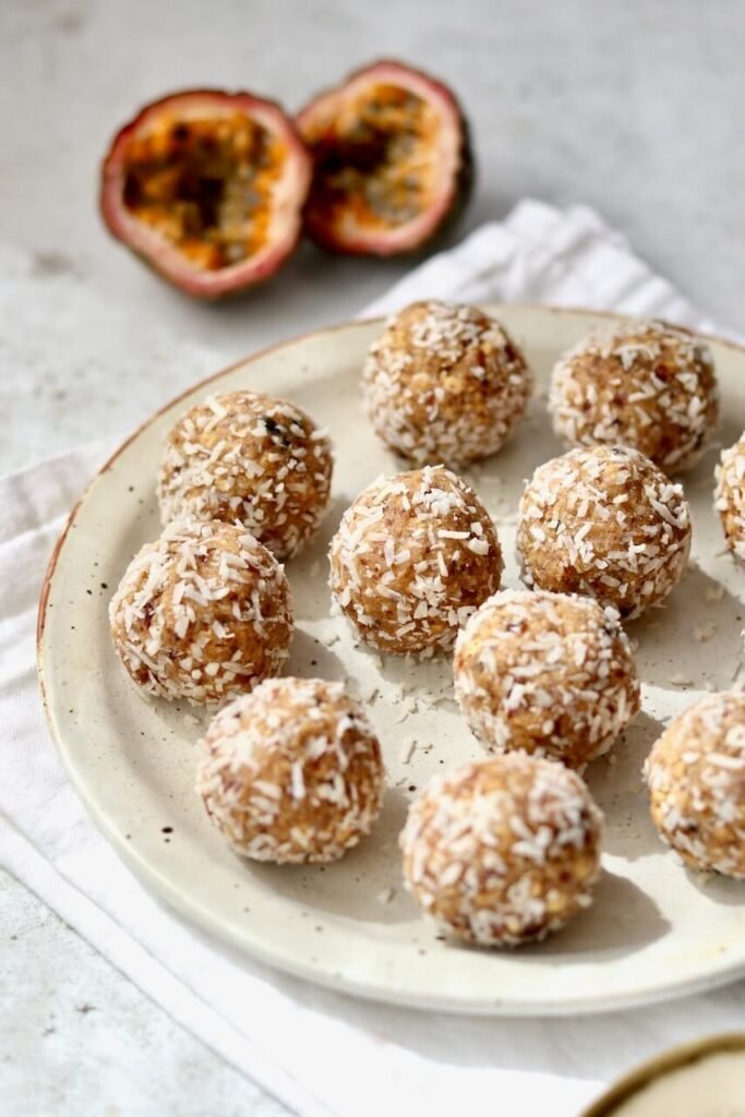 A pile of coconut-coated passion fruit protein bites, a no-bake gluten-free high-protein snack