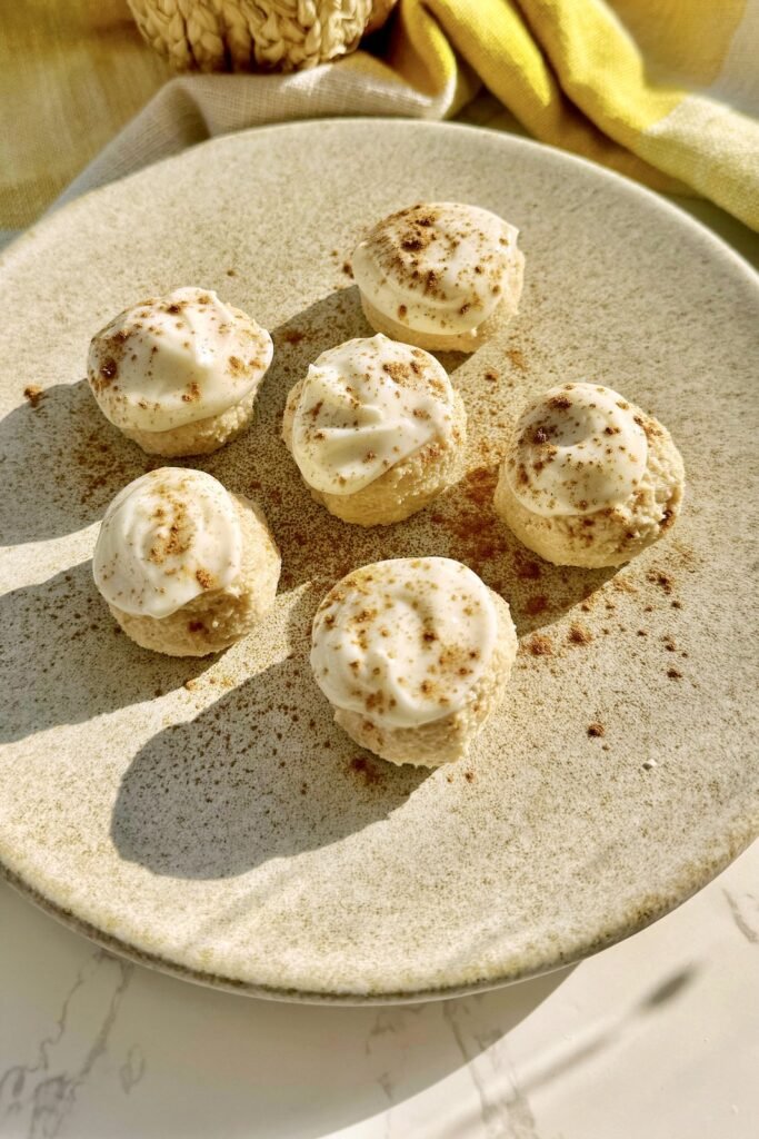 Six pumpkin spice cheesecake bites on a plate dusted with spice