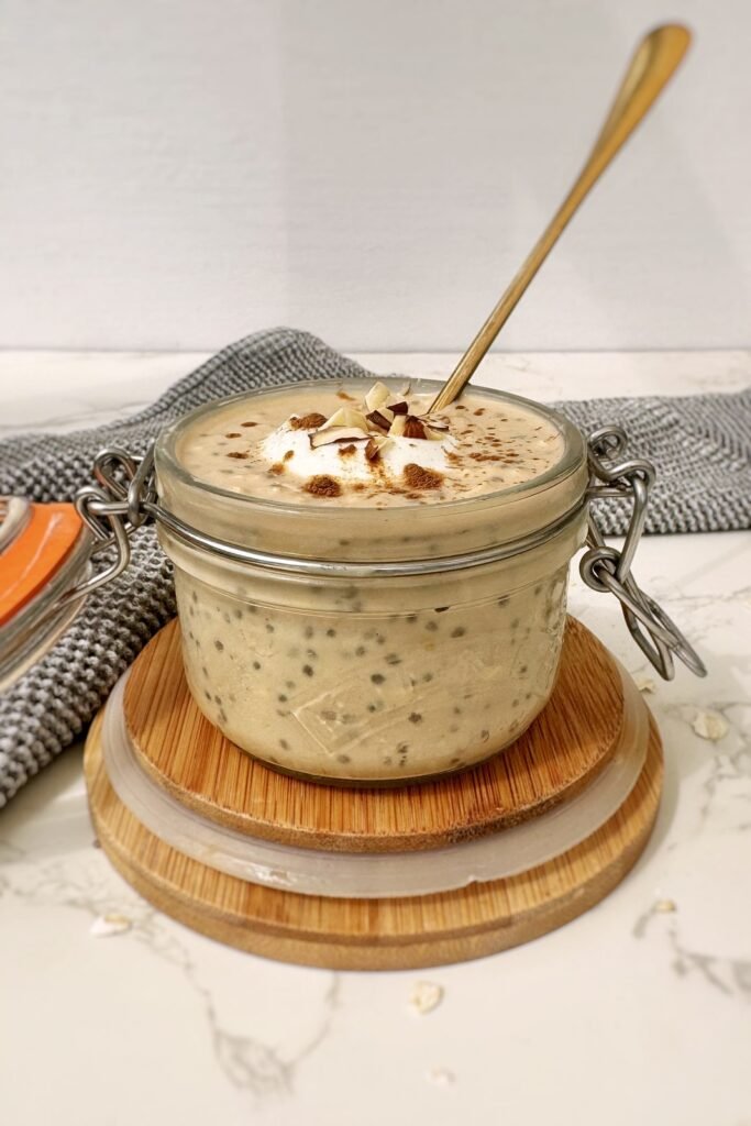 Top-down shot of pumpkin spice latte overnight oats in a glass jar with a hinged lid, dusted with cinnamon.