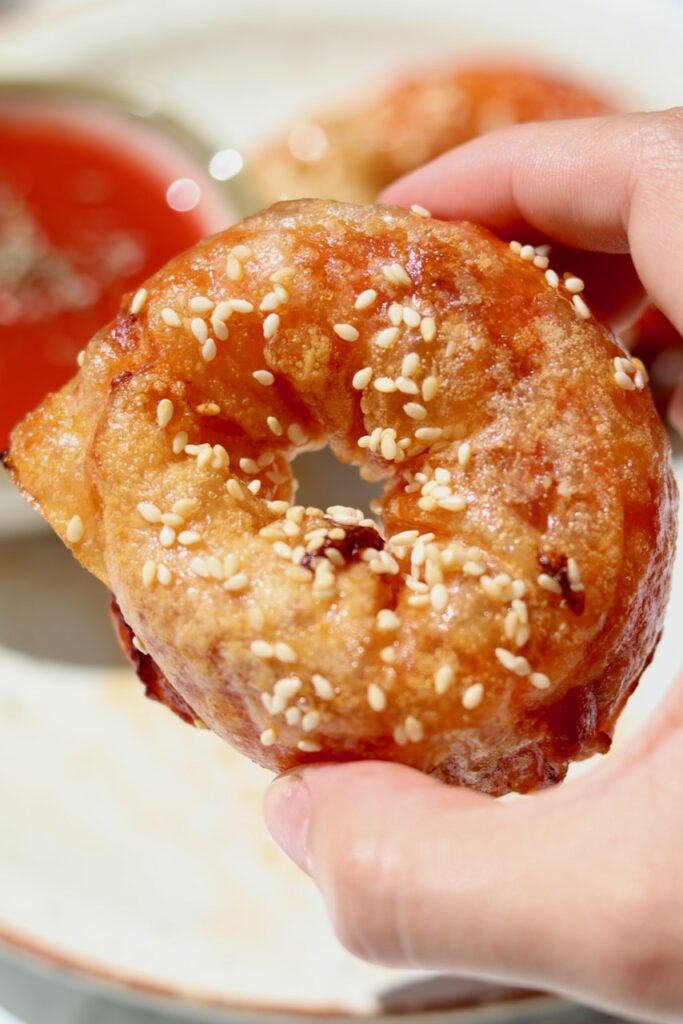 Crispy rice paper pizza bagel held up close, topped with sesame seeds