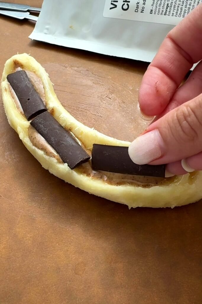 Pressing dark chocolate chunks into the almond butter filled banana