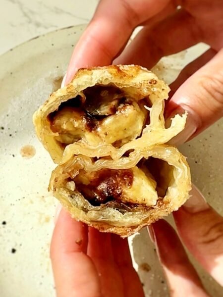 Snickers spring rolls cut open to show melted chocolate and almond butter inside soft banana