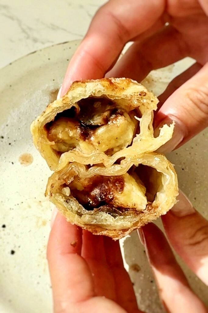 Snickers spring rolls cut open to show melted chocolate and almond butter inside soft banana
