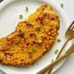 Sweet potato wrap folded over on a speckled plate with spring onion and a gold fork