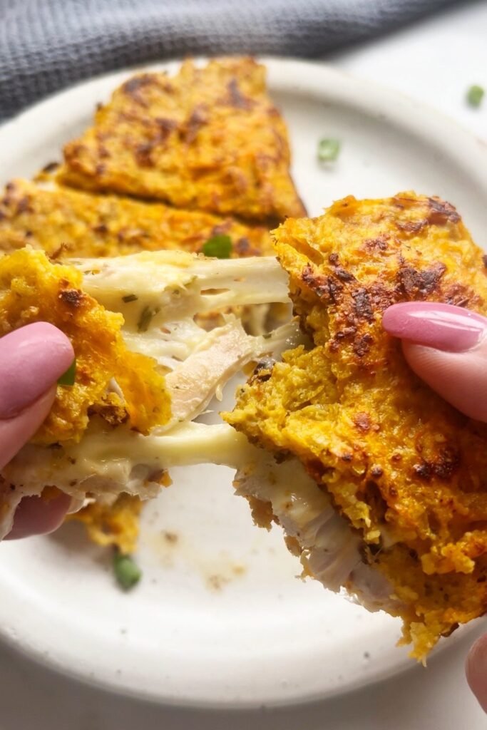 Holding a sweet potato wrap with melted cheese stretching from the filling