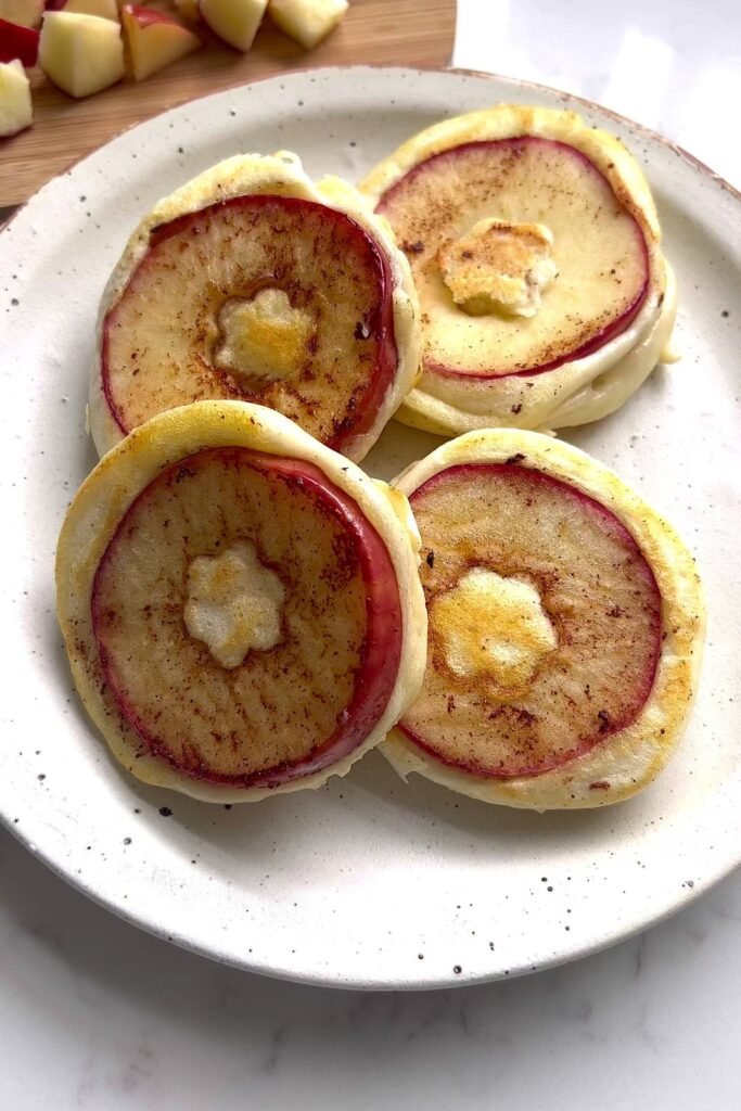Three apple cinnamon pancakes on a white speckled plate