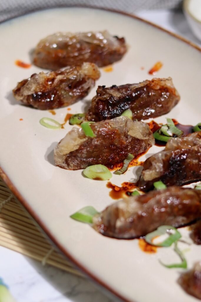 Close up of a crispy rice paper duck dumpling showing the golden seared base