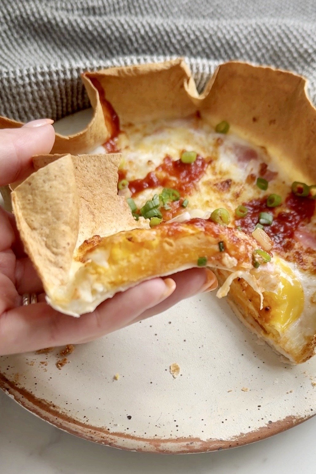 A slice of ham and cheese tortilla quiche being lifted from the plate showing the soft egg and melted cheese