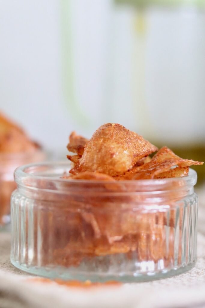 Homemade BBQ rice paper chips piled in a small glass jar