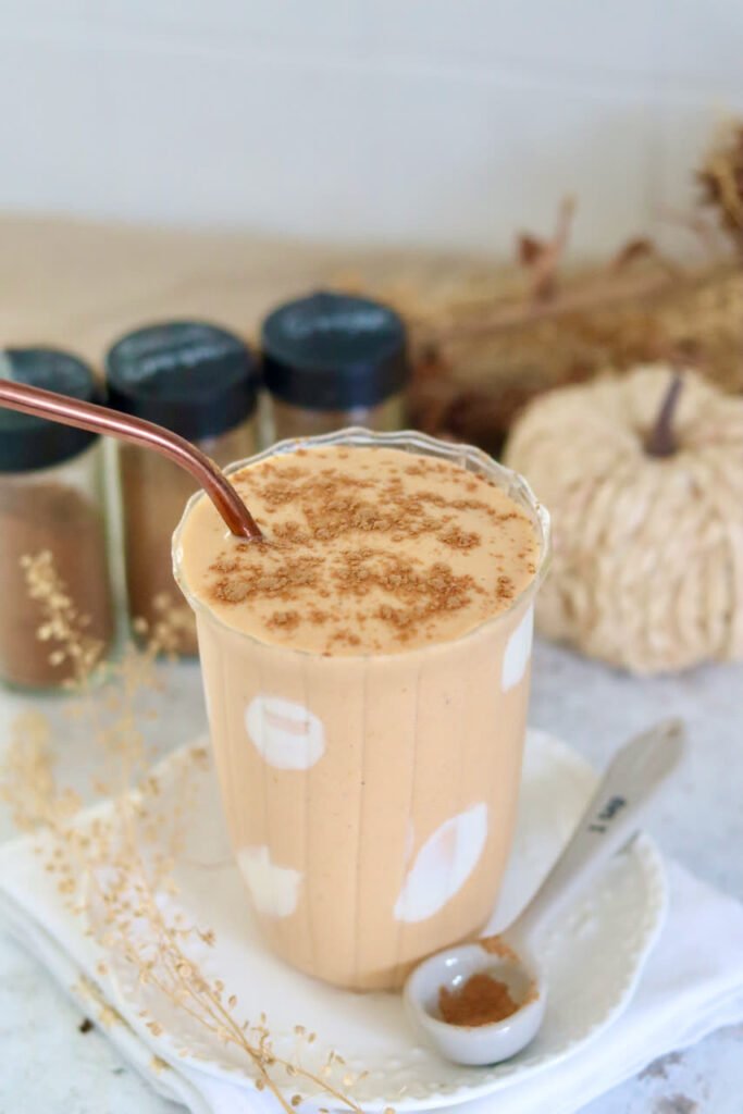Protein pumpkin smoothie in a fluted glass dusted with pumpkin spice