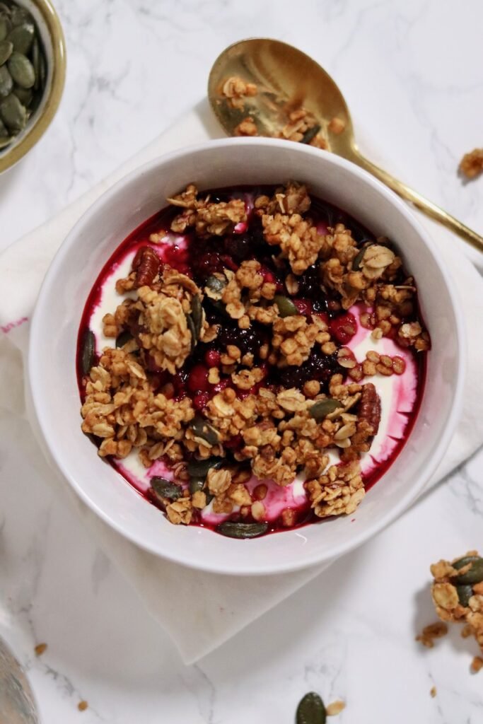 Yoghurt bowl topped with pumpkin granola and berry compote