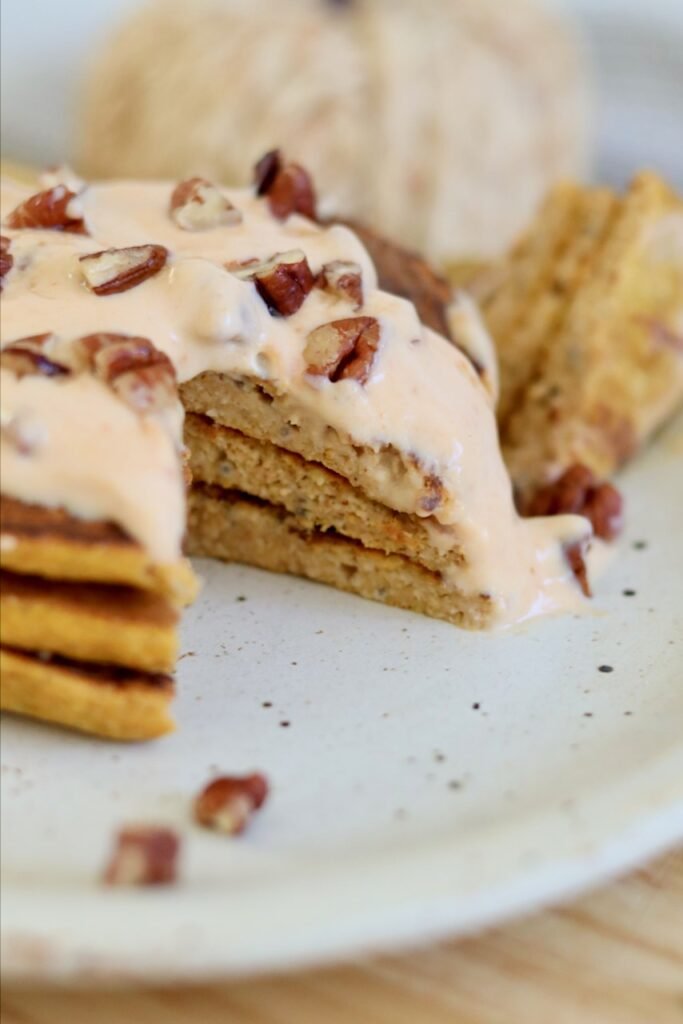 Close up cross section of a pumpkin pancake stack with chopped pecans on top
