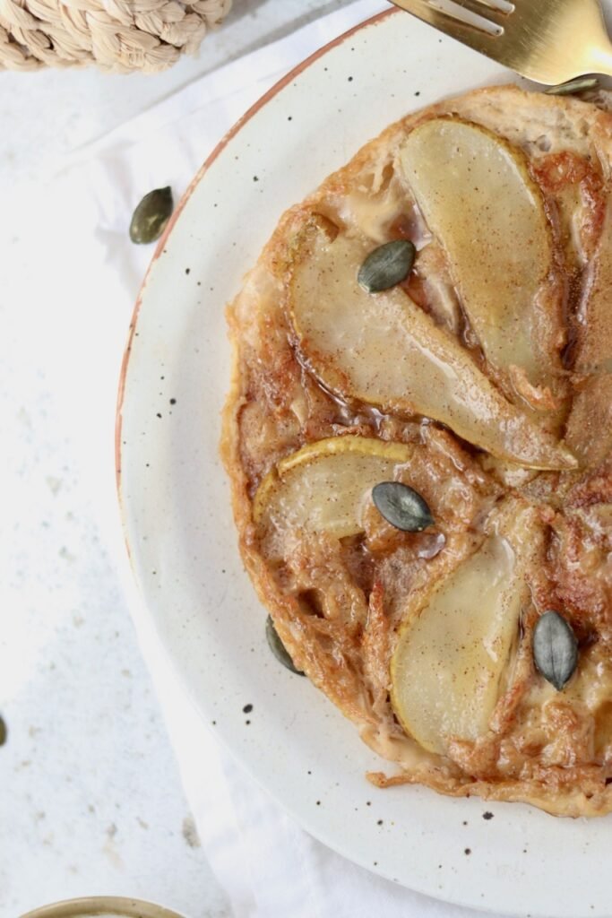 Close up of rice paper tarte tatin showing the fanned pear slices and pumpkin seed garnish