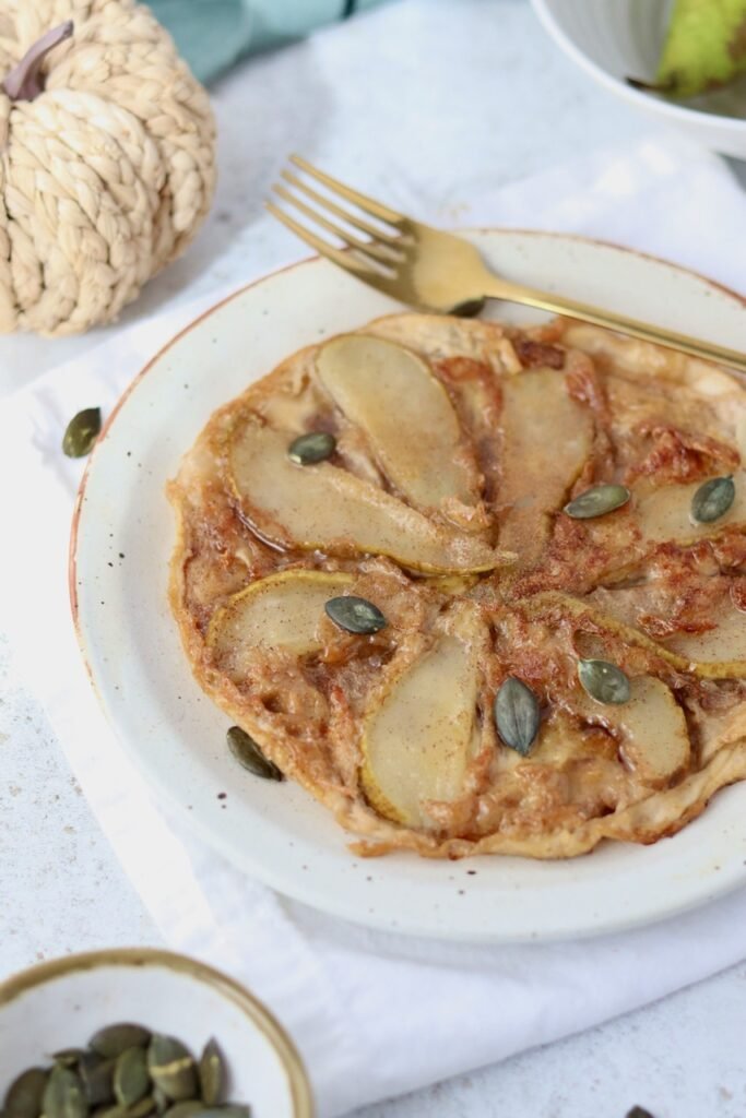 Rice paper tarte tatin served with a gold fork and pumpkin seeds, showing the crisp caramelised edge