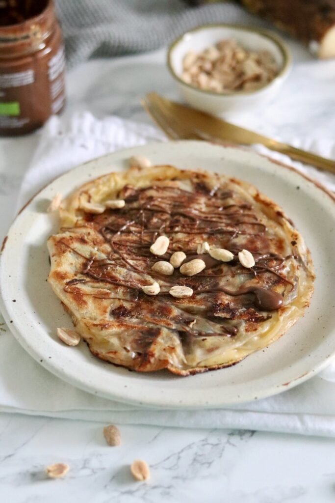 Snickers rice paper crepe topped with chocolate drizzle and chopped peanuts