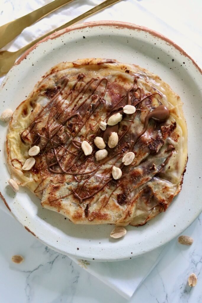 Close up of a gluten free snickers rice paper crepe with banana and chocolate