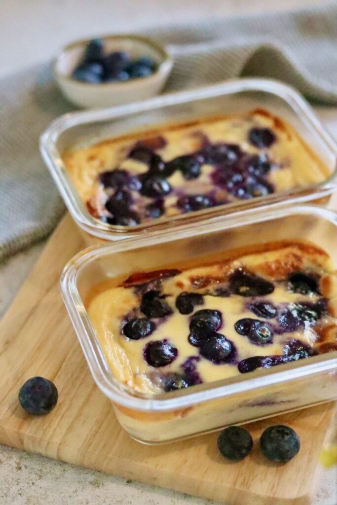 Two glass dishes of blueberry baked yogurt soufflé with fresh blueberries