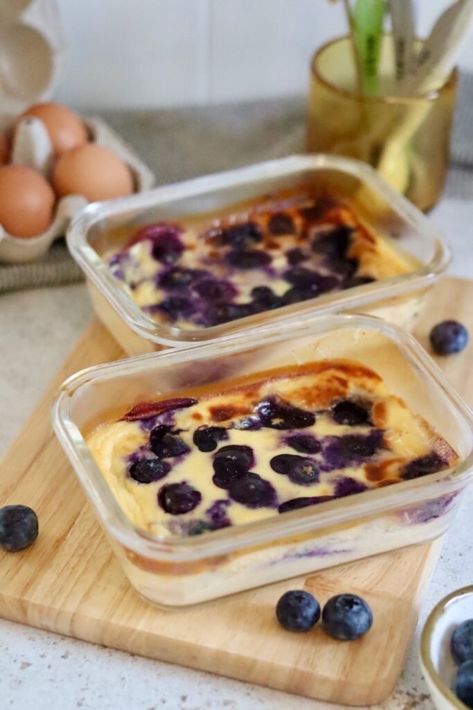 Two glass dishes of blueberry baked yogurt soufflé with fresh blueberries and eggs