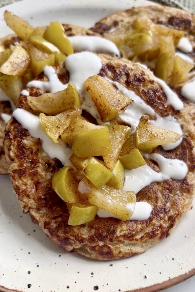 Cottage cheese oat pancakes with a warm apple topping and yogurt drizzle