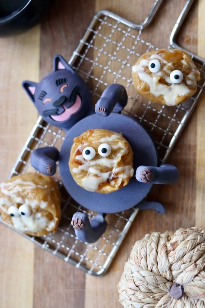 Overhead Halloween spread of pumpkin rice paper muffins decorated as mummies