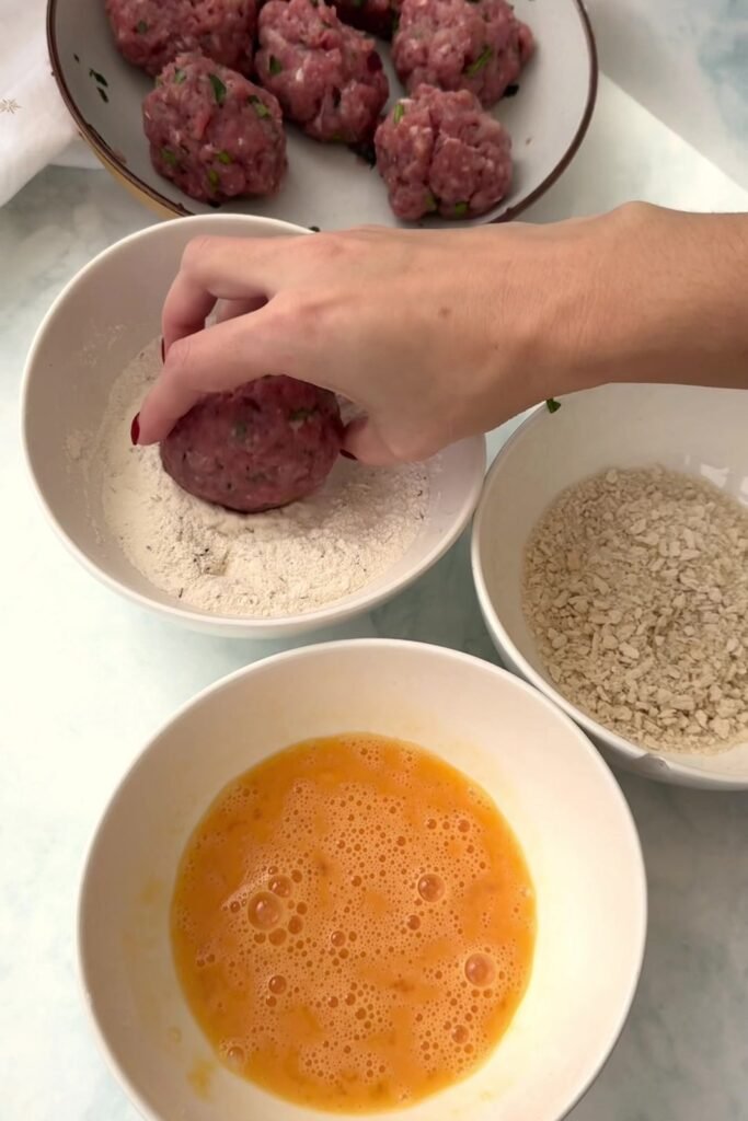 Scotch eggs being coated in flour, beaten egg and panko breadcrumbs