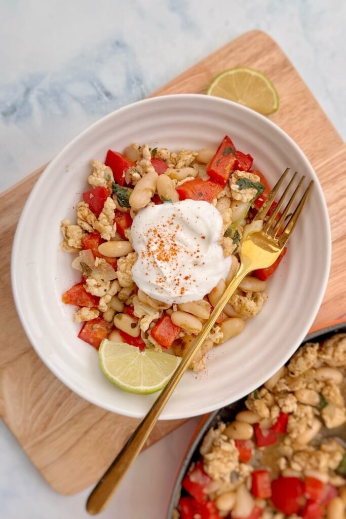 Bowl of turkey and white bean chili topped with Greek yogurt, smoked paprika and lime