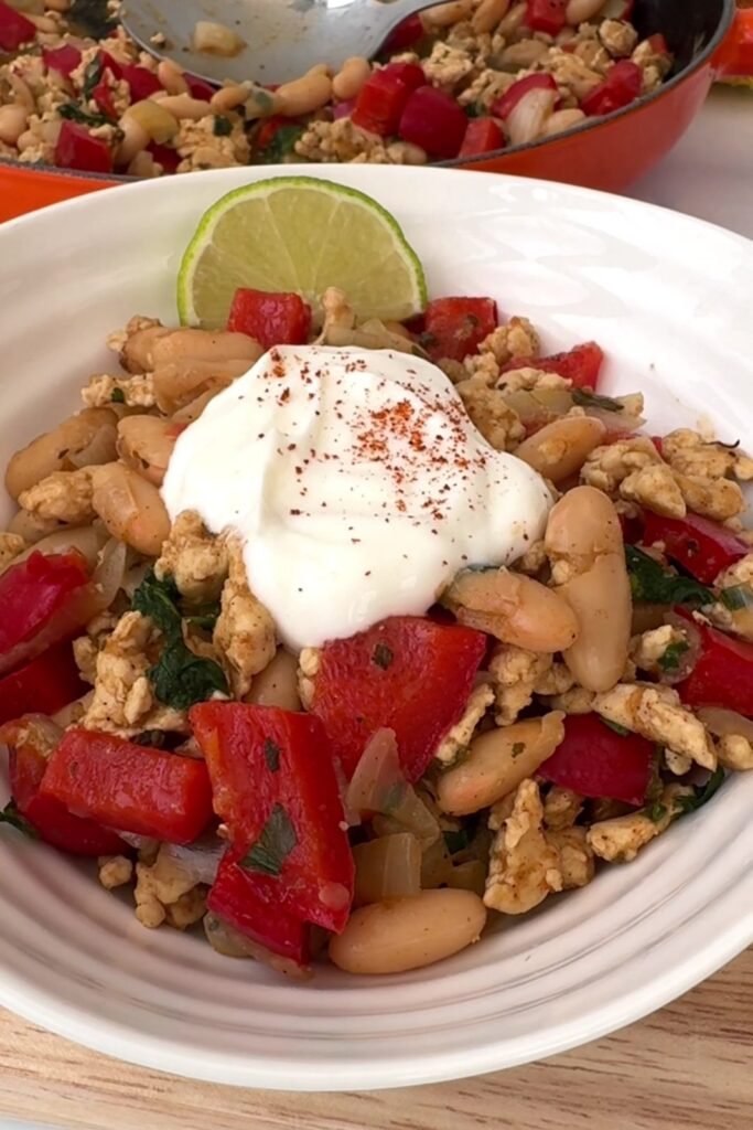 White bean turkey chili served in a bowl with Greek yogurt and a lime wedge